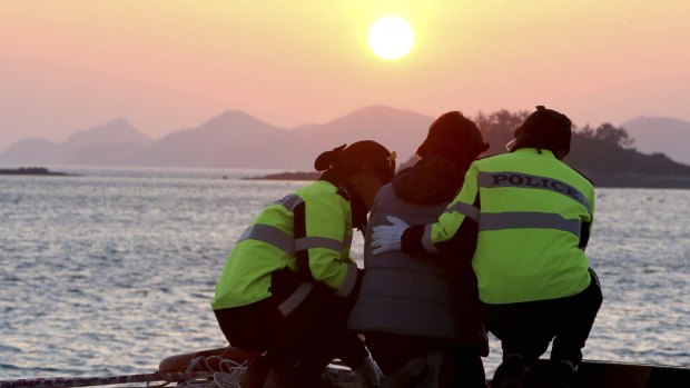 Police comfort a Sewol family member waiting for news at the port of Jindo after the disaster.
