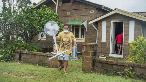 Joel Medil empties his Cyclone Debbie damaged house wearing a mask as protection from asbestos damage.