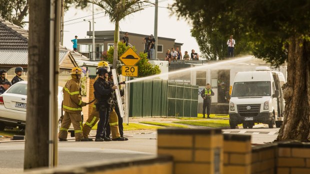 Emergency services personnel spray high pressure water into the home of a man who held police at bay during a siege at Noble Park.