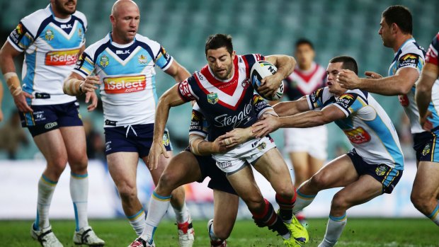 Hard to hold in the wet: Roosters fullback Anthony Minichiello tries to give the Gold Coast defence the slip.