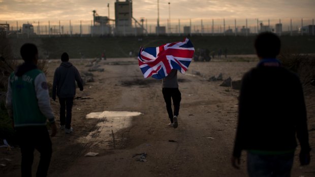 A man runs with a British flag in the Jungle, Calais. Many migrants at the camp want to settle in the UK, not France.