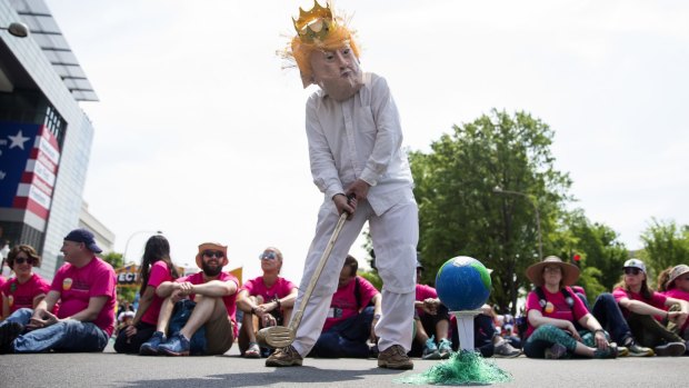 A demonstrator dressed as King Trump prepares to swing a golf club at the Earth during the People's Climate Movement March in Washington.