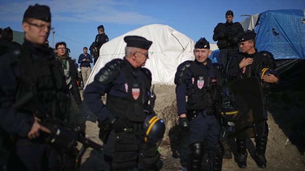 French police search through migrant tents at the "Jungle" before authorities demolish the site on Tuesday.