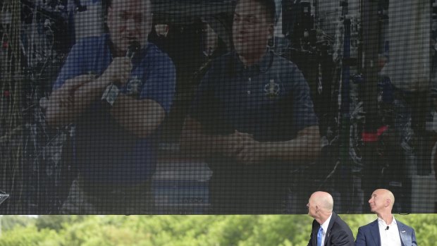 Amazon chief executive Jeff Bezos, right, and Florida Governor Rick Scott watch a video message from Nasa astronauts Scott Kelly, left, and Kjell Lindgren, aboard the International Space Station, during a news conference unveiling the new Blue Origin rocket at the Cape Canaveral Air Force Station in Florida.