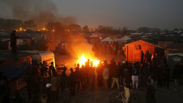 People gather around a fire in the camp known as the Jungle near Calais on Tuesday.