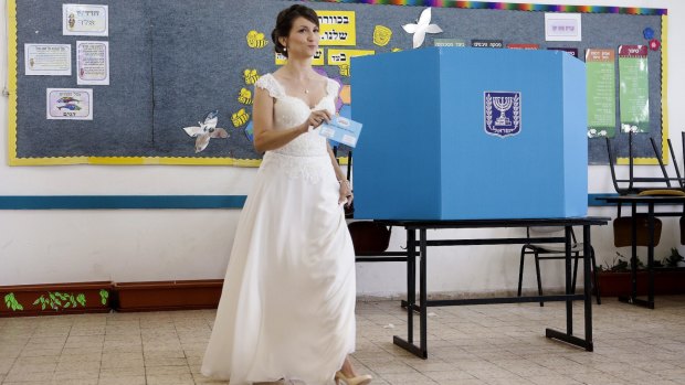 An Israeli bride prepares to cast her vote at a polling station in Holon, central Israel, on Tuesday. Israelis are voting in early parliamentary elections following a campaign focused on economic issues such as the high cost of living. 