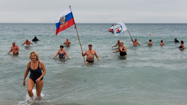 Crimean people wave a Russian national flag celebrating Orthodox Christmas in the Black Sea in Yevpatoriya earlier this year.