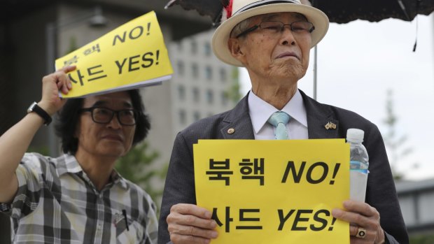 South Koreans hold signs during a rally on Monday in support of a plan to deploy an advanced US missile defence system. The sign reads "No, North Korea's Nuclear; Yes, THAAD."