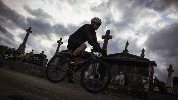 A cyclist rides through the Melbourne General Cemetery, Parkville.