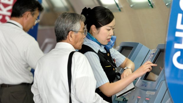 An ANA staff member helps a passenger at self-serve check-in.