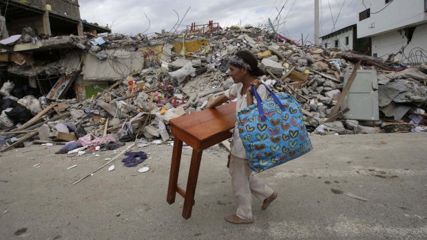 A woman carries a table through the street after an earthquake in Ecuador on Sunday. 