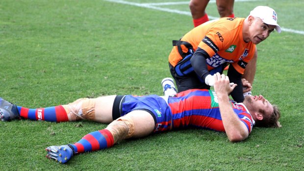 Down: Brendan Elliot of the Knights is treated by Tony Ayoub after being felled during Newcastle's clash with South Sydney on Saturday. 