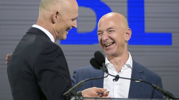 Florida Governor Rick Scott (left) and Amazon founder Jeff Bezos share a joke as Mr Scott presents Mr Bezos with the Governor's Business Ambassador Award during a news conference unveiling the new Blue Origin rocket program.