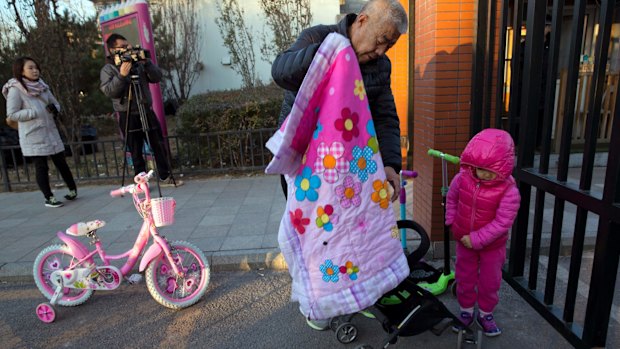 An elderly man escorts a child to the RYB kindergarten in Beijing on Friday.