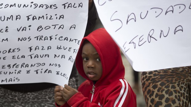 A boy stands between signs during a protest against violence, at the burial of Roseli dos Santos de Jesus killed by a stray bullet during a shooting between police and drug traffickers at a cemetery in Rio on Tuesday.