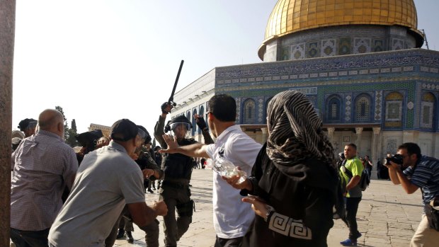 Israeli police officers threaten Palestinians near the Dome of the Rock in July this year.