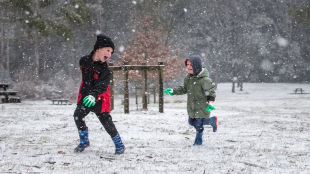 Jamie and Ryan Haworth play in the falling snow at Day's Picnic Area, Mount Macedon.
