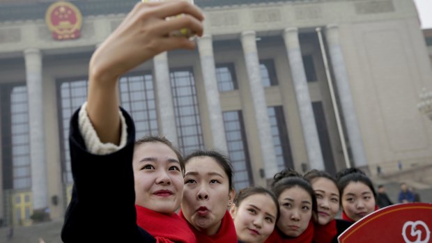 Hostesses, who serve party delegates, take a selfie in front of the Great Hall of the People on Thursday. 