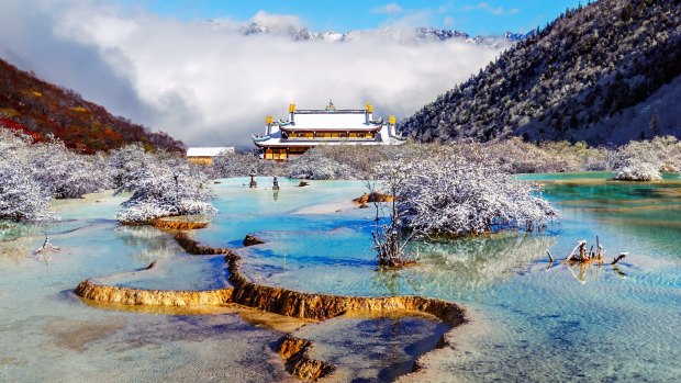 The multi-coloured pond with Huanglong Middle Temple on background in the Huanglong National Park.
