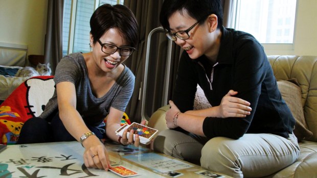 Log Chen, right, and her partner Chalynn Hsueh joke as they lay out astrology cards in their home in Taipei, Taiwan. 