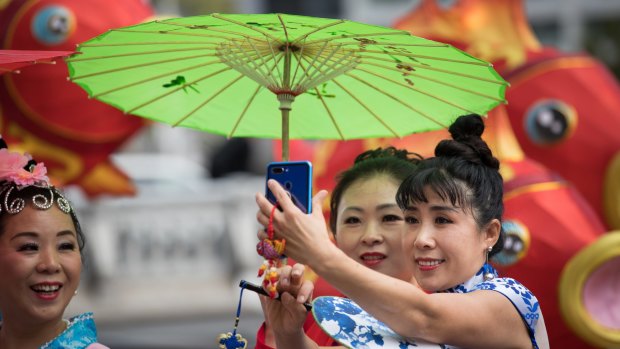 Women in traditional costumes pose for photos ahead of Chinese New Year celebrations in Melbourne.