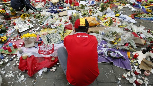 Two men help re-adjust the tributes left for the victims of the recent bomb attacks in Brussels.