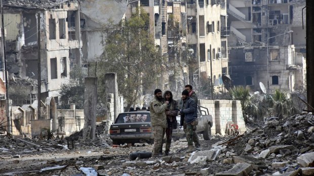 Syrian troops and pro-government gunmen stand in the Ansari neighbourhood, east Aleppo, on Friday.