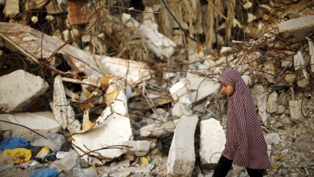 A Palestinian girl walks past a house that witnesses said was destroyed by Israeli shelling during a 50-day war last year.