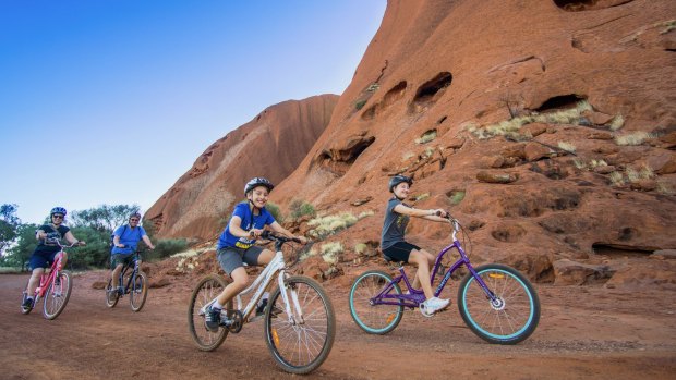 A group of cyclists follows the trail around Uluru.