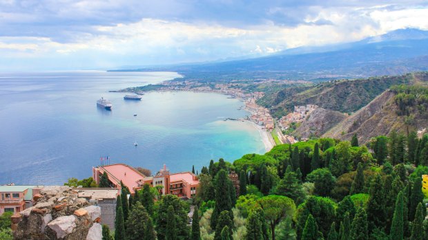 From the old ruins of Taormina, tourists can see the bay of Sicily.