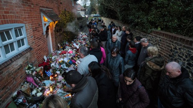 Fans gather around floral tributes left outside the Oxfordshire home of British pop singer George Michael on December 27, 2016 in Goring, England.