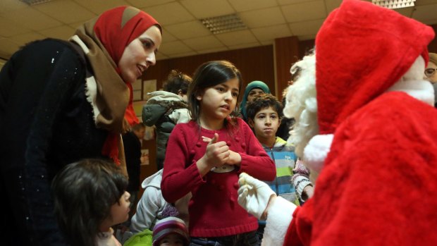 A child speaks to a volunteer dressed as Santa Claus at a migrant shelter in Berlin on Monday. 