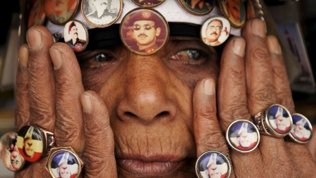 A woman supporting former dictator Ali Abdullah Saleh wears rings and badges showing Saleh and his son Ahmed Ali Saleh (in sunglasses, above her nose)  during a rally in the Yemeni capital Sanaa.