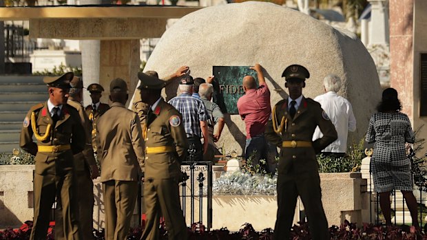 Workers place a plaque with the word 'Fidel' on the tomb holding the remains of the former Cuban president.