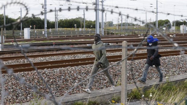 Migrants make their way along train tracks as they attempt to access the Channel Tunnel in Frethun, near Calais, on Wednesday.