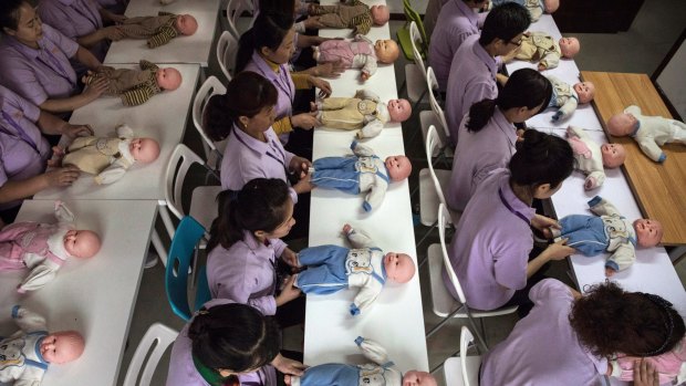 Chinese women train on dolls to become qualified nannies at the Ayi University in Beijing.