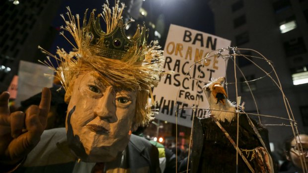 A demonstrator wearing a mask in the likeness of US President Donald Trump protests against his executive order in Los Angeles.