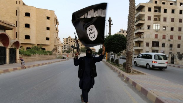 A jihadist holds an Islamic State flag held aloft in Raqqa, Syria.
