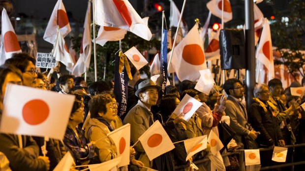 People wave Japanese national flags in support of Shinzo Abe during a campaign rally in Tokyo, on Saturday.
