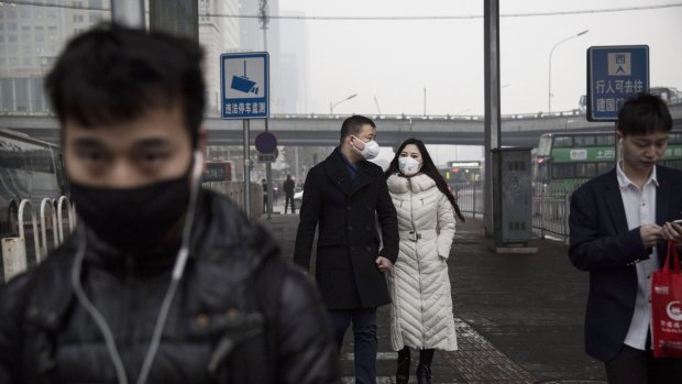 A  Chinese couple wear masks as they walk together to work during heavy pollution in Beijing last month. 