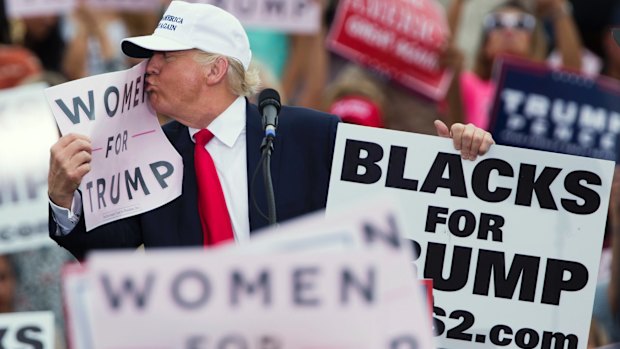 Republican presidential candidate Donald Trump kisses a Women for Trump sign at a campaign rally in Florida. 