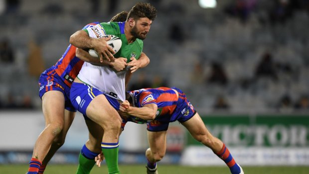 Dave Taylor of the Raiders (centre) is tackled by Daniel Levi of the Newcastle Knights.