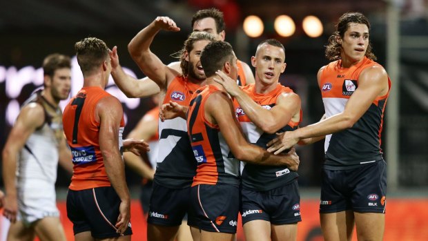 Tom Scully of the Giants celebrates with teammates after kicking a goal against Hawthorn. 