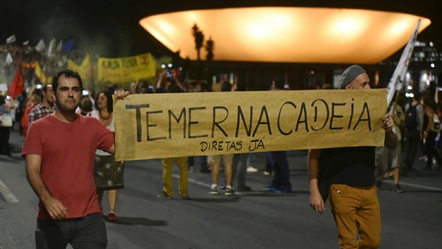 Demonstrators carry a sign that reads in Portuguese "Temer in jail" and calls for direct elections in Brasilia on Thursday.