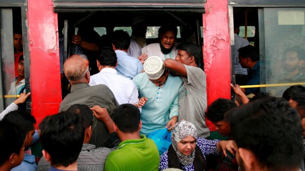Locals try pile into an overcrowded bus in Bangladesh.