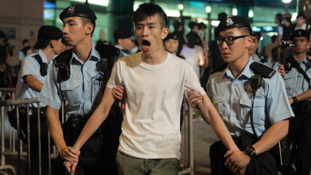 A pro-democracy activist is arrested by police in Golden Bauhinia Square.