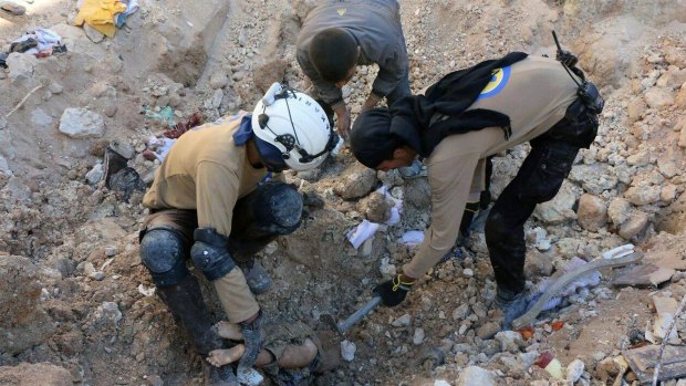 In reality: Members of Civil Defence removing a dead body from under the rubble after airstrikes hit in Aleppo last month.