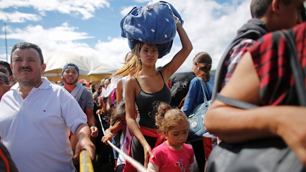 A woman carrying a bundle on her head waits in line to cross the border into Colombia through the Simon Bolivar International Bridge in San Antonio del Tachira, Venezuela. 