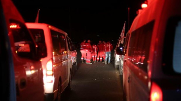 Syrian Arab Red Crescent members gather near their ambulances to evacuate the sick from eastern Ghouta, Syria.