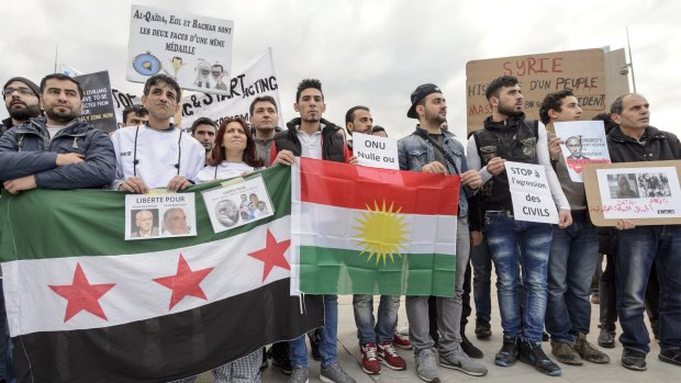 Protesters hold posters and flags during a demonstration against the Syrian regime during Syrian Peace talks in Geneva, Switzerland, on Friday.